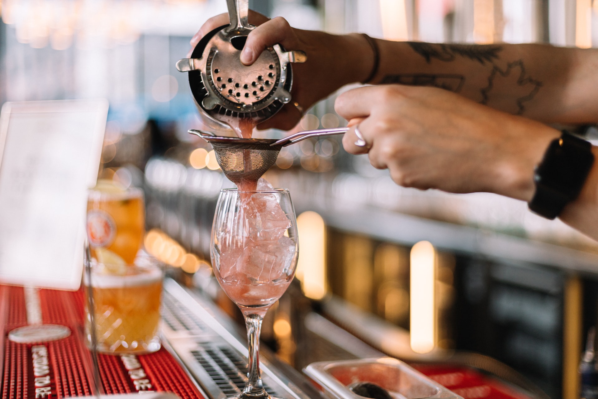 a bartender pours a drink into a glass